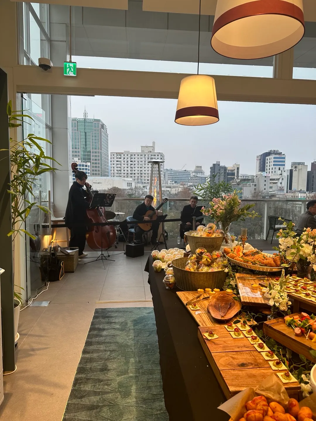 7층 라운지에서 테라스로 이어지는 뷔페 테이블과, 테라스에서 연주하는 재즈 트리오(더블베이스·기타)